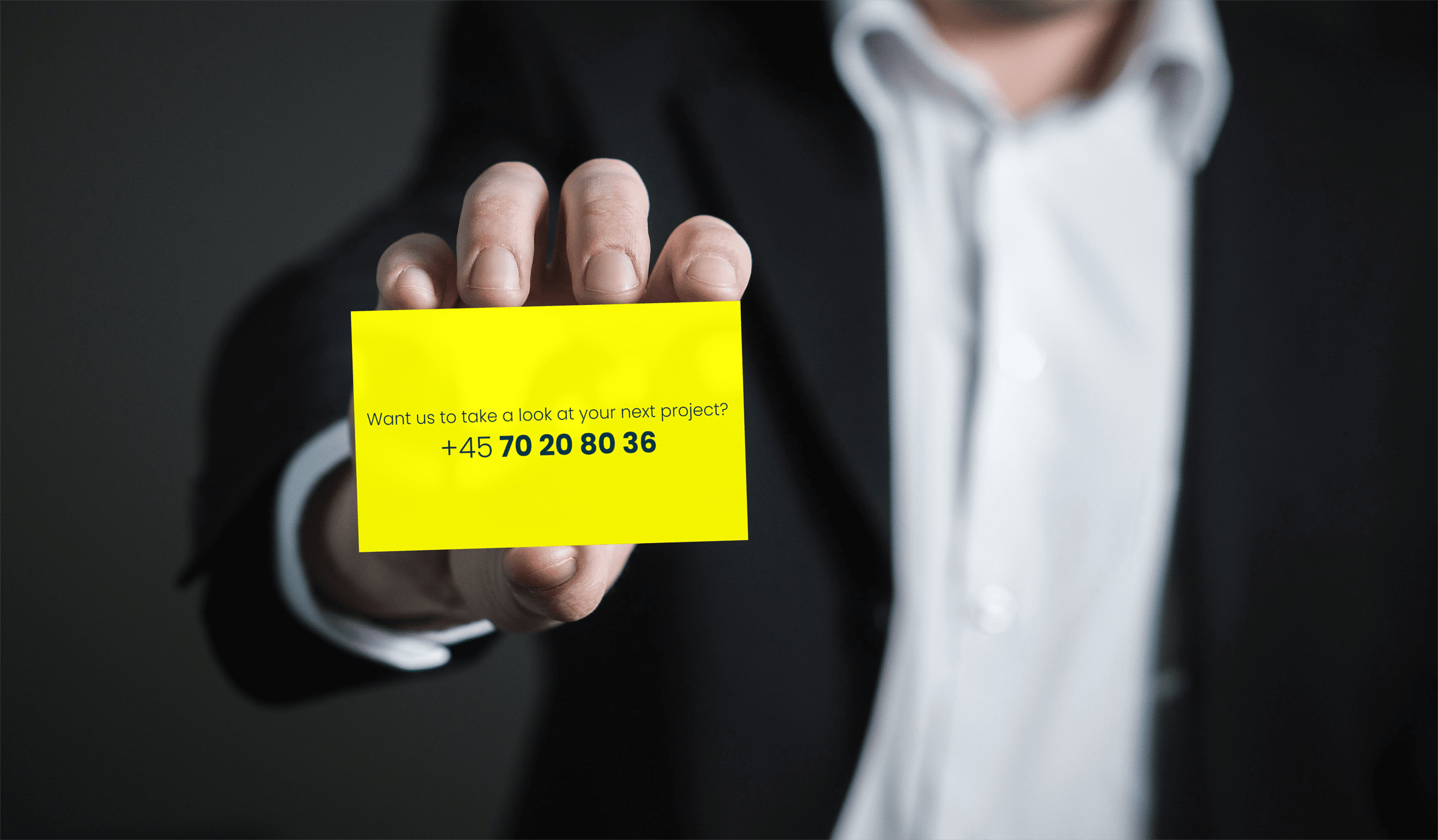 a man holding card with text "want us to take a look at your next project? phone number : +457020803